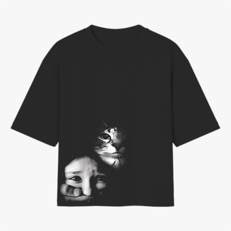 Camiseta com estampa frontal de um rosto de gato e o rosto de uma criança que olha através de uma mão, ambos sobrepostos, criando um efeito intrigante.