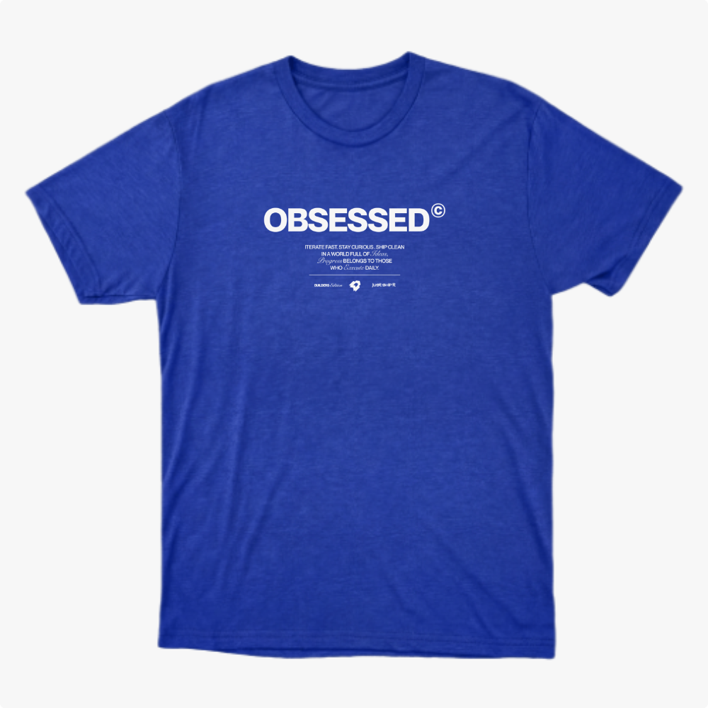 Camiseta com estampa frontal de texto grande "OBSESSED" seguido por linhas menores que incluem mensagens inspiradoras e dois logotipos pequenos abaixo.