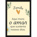 Quadro com estampa de mensagem "Família Aqui mora o amor que sustenta nossos dias" entre ramos de folhas, coração laranja e margarida.
