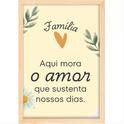 Quadro com estampa de mensagem "Família Aqui mora o amor que sustenta nossos dias" entre ramos de folhas, coração laranja e margarida.