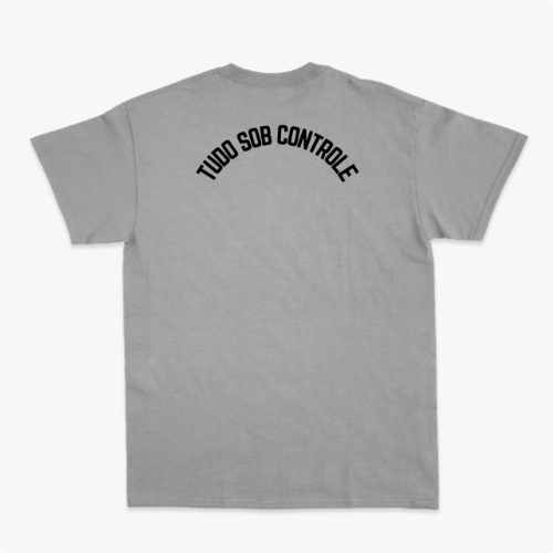 Camiseta com estampa frontal de gato preto segurando um copo, envolto em formas abstratas, e estampa traseira com texto em arco "TUDO SOB CONTROLE".