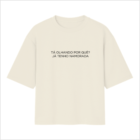 Camiseta com estampa frontal de frase humorística "TÁ OLHANDO POR QUÊ? JÁ TENHO NAMORADA" em letras maiúsculas, proporcionando um toque divertido e direto.