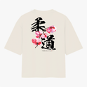 Camiseta com estampa frontal de texto "YAMA JIU JITSU" em letras pequenas e estampa traseira de caracteres japoneses grandes com flores estilizadas.