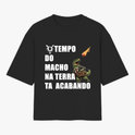 Camiseta com estampa frontal de dinossauro em terno segurando uma pasta, com meteoro em queda e a frase "TEMPO DO MACHO NA TERRA TA ACABANDO".