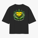 Camiseta com estampa frontal de rosto sorridente decorado com folhas e texto "Elevate Your Frequency" emoldurado por elementos naturais e estampa traseira de símbolo geométrico simples próximo à gola.