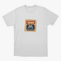 Camiseta com estampa frontal de um selo retangular retrô com o ano "1986" no topo e a inscrição "Rede Manchete" abaixo, separado por um símbolo estilizado.