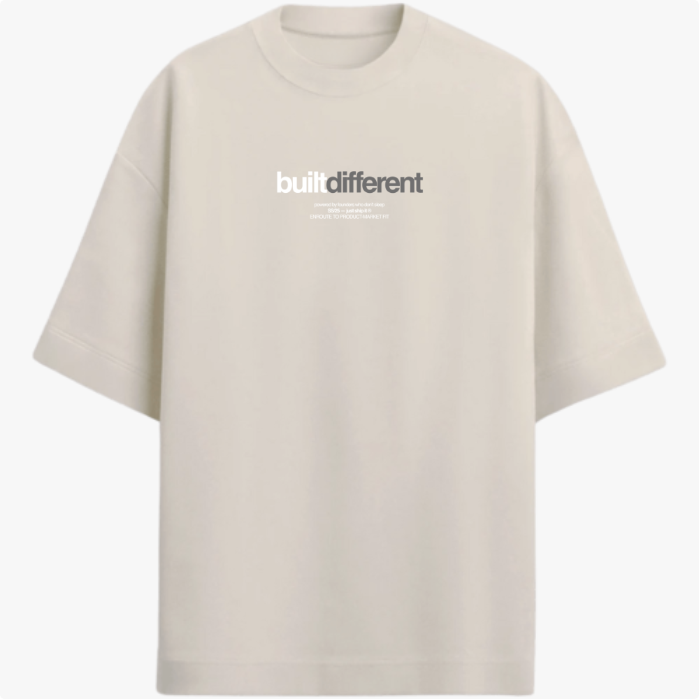 Camiseta com estampa frontal de texto "built different" em destaque, acompanhado por linhas menores com frases adicionais, em um estilo moderno e impactante.