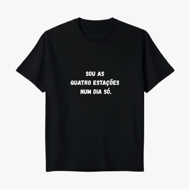 Camiseta com estampa frontal de texto em forma de frase que diz "SOU AS QUATRO ESTAÇÕES NUM DIA SÓ." em fonte de estilo marcante e legível.