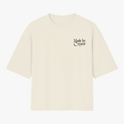 Camiseta com estampa frontal de "Made by Creator" em letras estilizadas e estampa traseira de "Made by Creator" acompanhada por ilustração de flores coloridas.