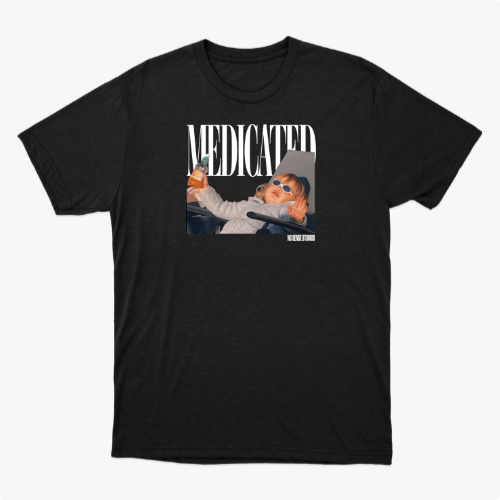 Camiseta com estampa frontal de uma criança em um carrinho, usando óculos escuros, segurando uma mamadeira, com a palavra "MEDICATED" ao fundo.