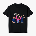 Camiseta com estampa frontal de três pessoas celebrando, sendo uma delas segurando um grande troféu acima da cabeça, transmitindo uma cena de vitória.