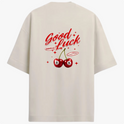 Camiseta com estampa traseira de cerejas tipo bola 8, cercadas por estrelas, acompanhadas das frases "Good Luck", "Good Vibes" e "Rawbeat".
