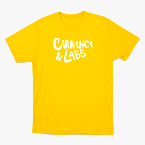 Camiseta com estampa frontal de letras estilizadas "Carranca & Labs" e estampa traseira de um desenho gráfico de figura caricata com expressão marcante.
