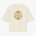 Camiseta com estampa frontal de emblema oval contendo texto "ATHOS", ferramentas, bigode, tesouras e barba, com detalhes e ornamentos circulares.
