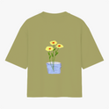 Camiseta com estampa frontal de texto em letras simples "Il raccolto è inevitabile." e estampa traseira de vaso azul com três flores amarelas e caule verde.