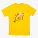 Camiseta com estampa frontal de personagens ao lado de pinheiro estilizado, acompanhados por flocos de neve dispersos pelo design.