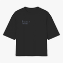 Camiseta com estampa frontal de texto em letras simples "Il raccolto è inevitabile." e estampa traseira de vaso azul com três flores amarelas e caule verde.