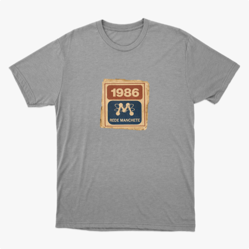 Camiseta com estampa frontal de um selo retangular retrô com o ano "1986" no topo e a inscrição "Rede Manchete" abaixo, separado por um símbolo estilizado.