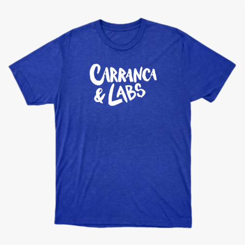 Camiseta com estampa frontal de letras estilizadas "Carranca & Labs" e estampa traseira de um desenho gráfico de figura caricata com expressão marcante.