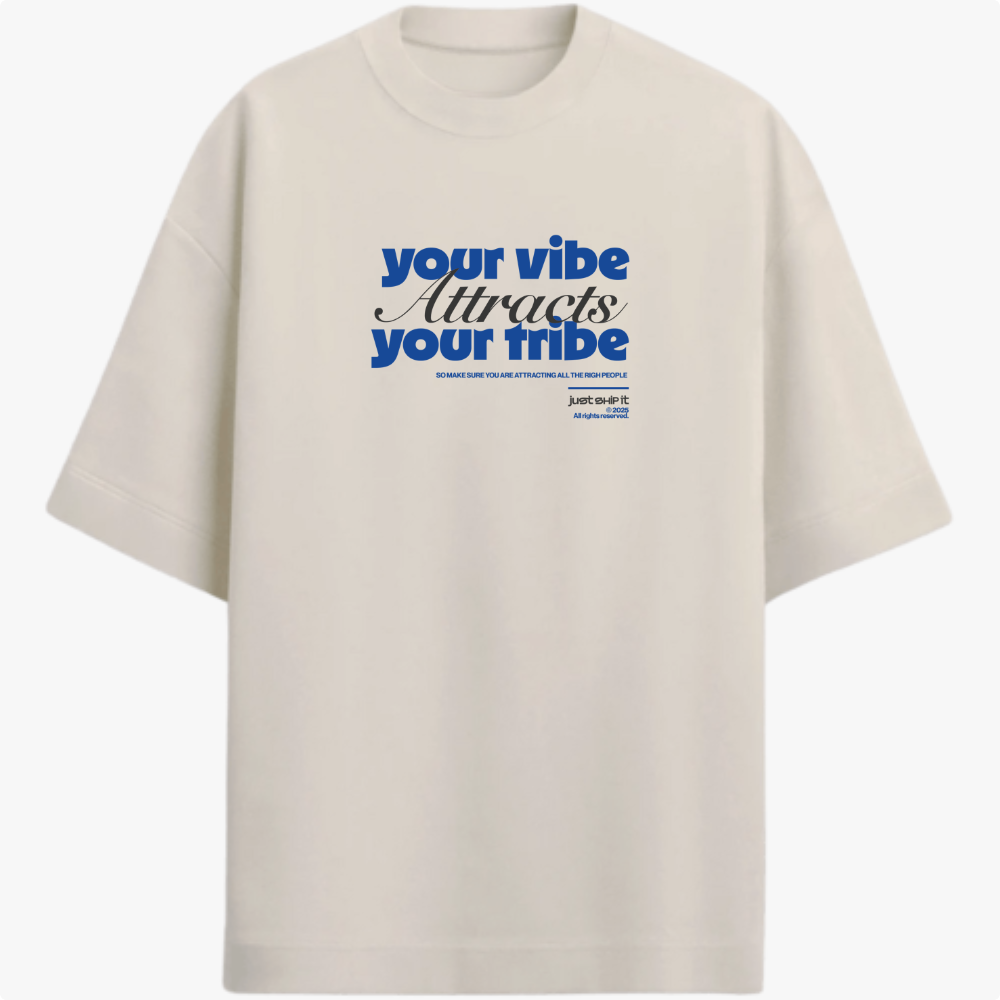 Camiseta com estampa frontal de texto estilizado "your vibe attracts your tribe" em letras grandes, acompanhada de pequenos detalhes textuais complementares.
