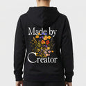 Moletom com estampa frontal de texto estilizado "Made by Creator" no lado superior esquerdo e estampa traseira de flores variadas sob o mesmo texto.