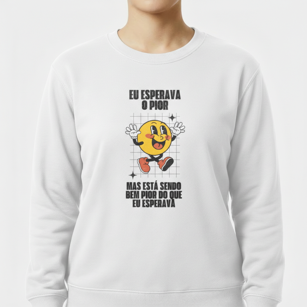 Moletom com estampa frontal de uma face sorridente com luvas e sapatos, cercada por grade sutil, acompanhada pela frase "Eu esperava o pior, mas está sendo bem pior do que eu esperava".