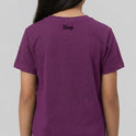 Camiseta com estampa frontal de um padrão geométrico com linhas curvadas e detalhes de texto "Kuarup" e "Xingu", e estampa traseira de "Xingu" centralizado.