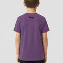 Camiseta com estampa frontal de um padrão geométrico com linhas curvadas e detalhes de texto "Kuarup" e "Xingu", e estampa traseira de "Xingu" centralizado.