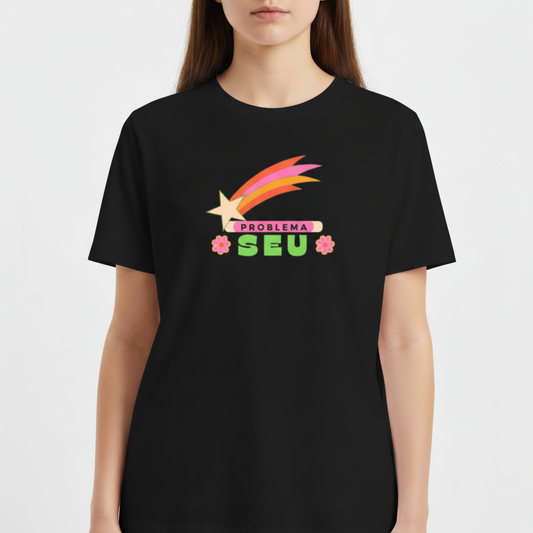 Camiseta com estampa frontal de faixa com estrela e arco colorido, texto "PROBLEMA SEU" em destaque e flores estilizadas nas laterais.