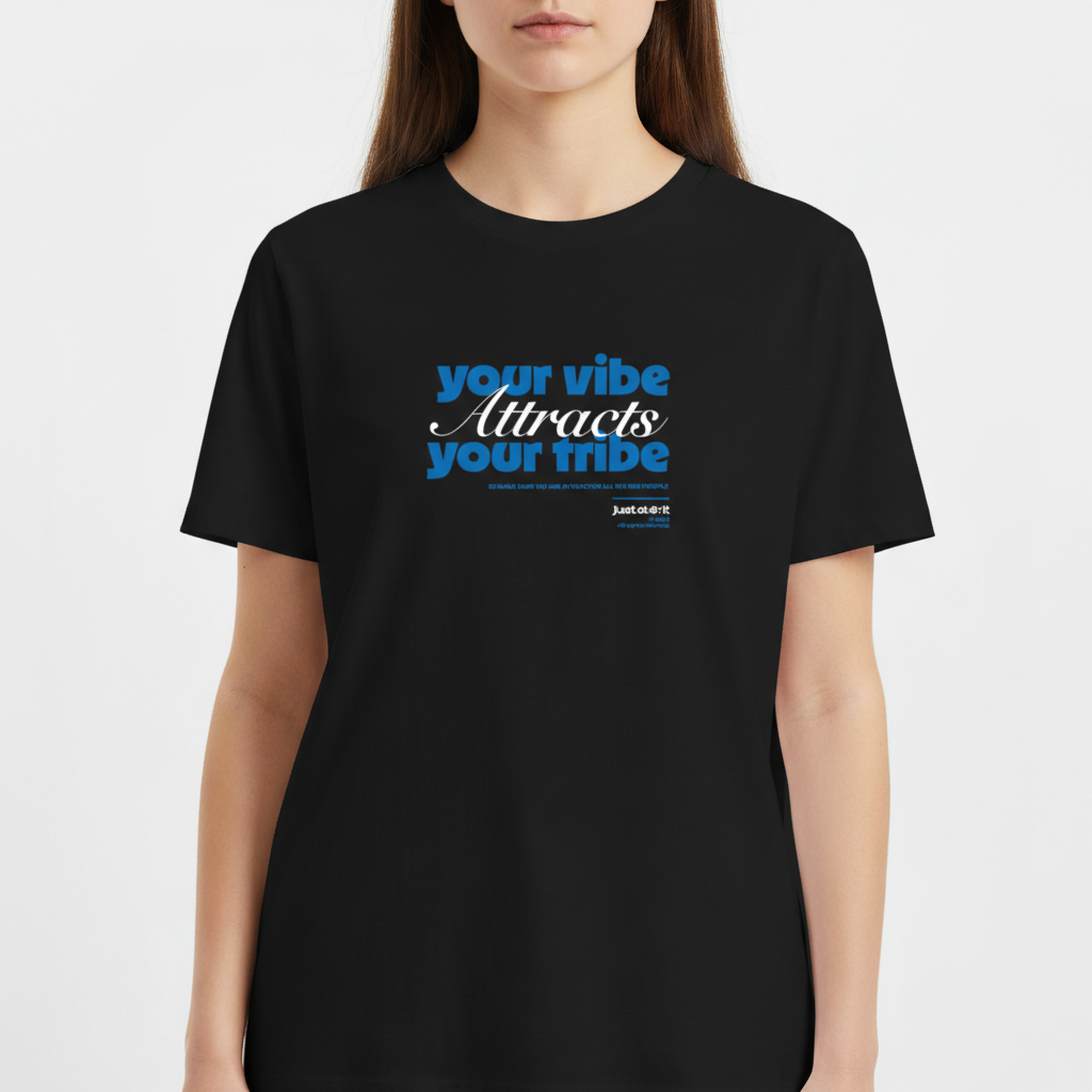 Camiseta com estampa frontal de frase inspiradora em fontes diversas, destacando "your vibe attracts your tribe," com pequenos detalhes textuais adicionais.