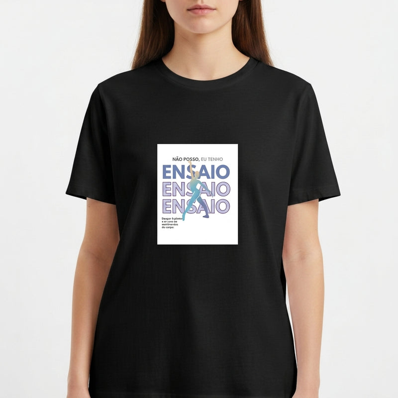 Camiseta com estampa frontal de texto "NÃO POSSO, EU TENHO ENSAIO" sobreposta a figura de uma bailarina em movimento, com detalhes textuais adicionais.