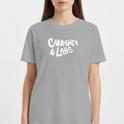 Camiseta com estampa frontal de letras estilizadas "Carranca & Labs" e estampa traseira de um desenho gráfico de figura caricata com expressão marcante.