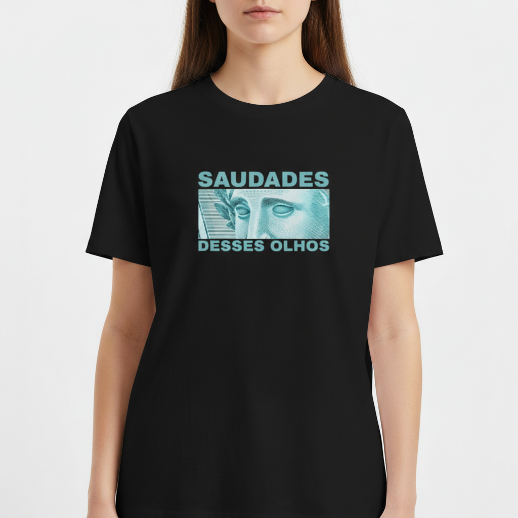 Camiseta com estampa frontal de ilustração de rosto de estátua com olhos destacados, ladeado por texto "SAUDADES DESSES OLHOS" em letras maiúsculas.
