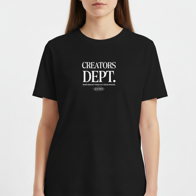 Camiseta com estampa frontal de texto "CREATORS DEPT." em fonte estilizada, acompanhado por uma frase descritiva e logotipo ovalado na parte inferior.