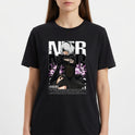 Camiseta com estampa frontal de personagem com cabelo prateado, vestindo traje estilizado, entre flores roxas, acompanhada de letras grandes e código de barras.