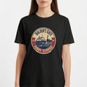 Camiseta com estampa frontal de um emblema circular apresentando um ferry estilizado, com inscrições que indicam "Baldur's Gate Ferry Service" e datas.