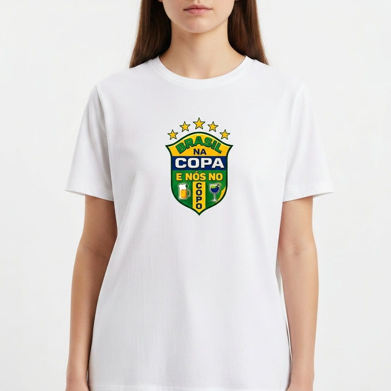 Camiseta com estampa frontal de brasão com cinco estrelas acima e frases "BRASIL NA COPA" e "E NÓS NO SOFÁ", acompanhado de duas bandeiras na lateral.