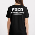 Camiseta com estampa frontal de "IRON Discipline" com halteres e estampa traseira de "FOCO TODOS OS DIAS" sobre "IRON DISCIPLINE" em letras destacadas.