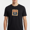 Camiseta com estampa frontal de um selo retangular retrô com o ano "1986" no topo e a inscrição "Rede Manchete" abaixo, separado por um símbolo estilizado.