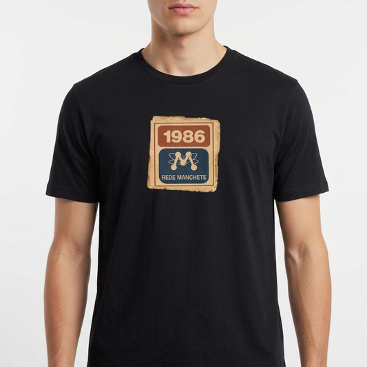 Camiseta com estampa frontal de um selo retangular retrô com o ano "1986" no topo e a inscrição "Rede Manchete" abaixo, separado por um símbolo estilizado.