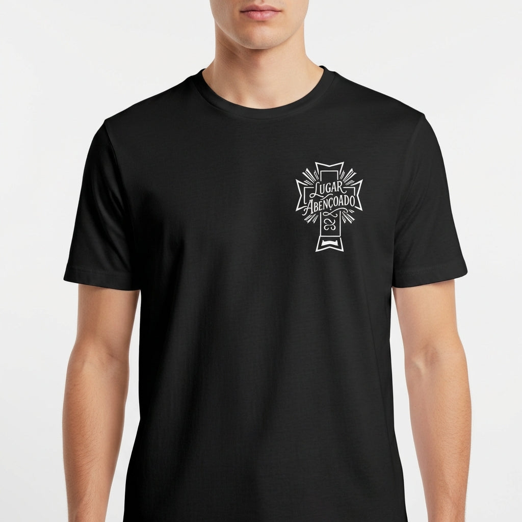 Camiseta com estampa frontal de cruz contendo a frase "Lugar abençoado" e símbolo decorativo, e estampa traseira de texto "LAB" em destaque.