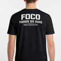 Camiseta com estampa frontal de "IRON Discipline" com halteres e estampa traseira de "FOCO TODOS OS DIAS" sobre "IRON DISCIPLINE" em letras destacadas.