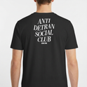 Camiseta com estampa frontal de escrita "ANTI DETRAN SOCIAL CLUB" e estampa traseira maior com a mesma mensagem, acompanhada por "NO BREAK STUDIOS".
