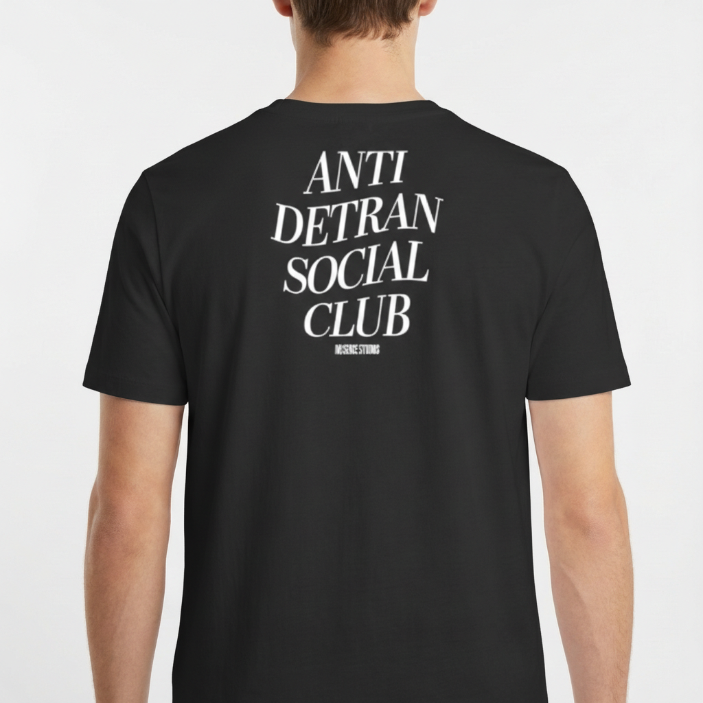 Camiseta com estampa frontal de escrita "ANTI DETRAN SOCIAL CLUB" e estampa traseira maior com a mesma mensagem, acompanhada por "NO BREAK STUDIOS".