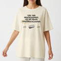 Camiseta com estampa frontal de lettering com mensagem de afirmação e imagem de lâmina, e estampa traseira de logotipo circular com ilustração central.