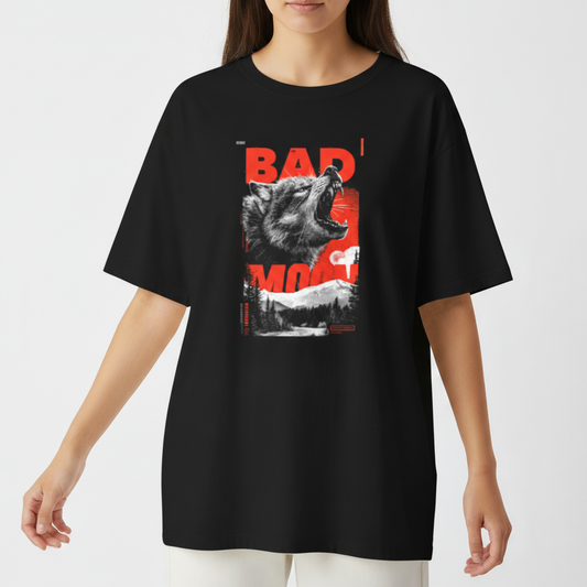 Camiseta com estampa frontal de um lobo uivante sobreposto a letras maiúsculas "BAD MOON", em contraste com uma paisagem de floresta ao fundo.