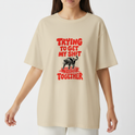 Camiseta com estampa frontal de um urso sobre blocos de construção com a frase em destaque "Trying to Get My Shit Together" em letras estilizadas.