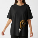 Camiseta com estampa frontal de um personagem amarelo parcialmente oculto, exibindo um olho expressivo e uma mão branca apontada para baixo.