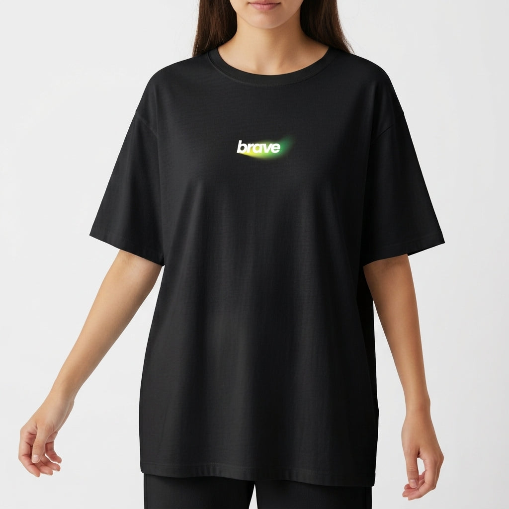 Camiseta com estampa frontal da palavra "brave" em letras estilizadas e efeito de brilho, e estampa traseira de texto "be brave" com desenho de leão.