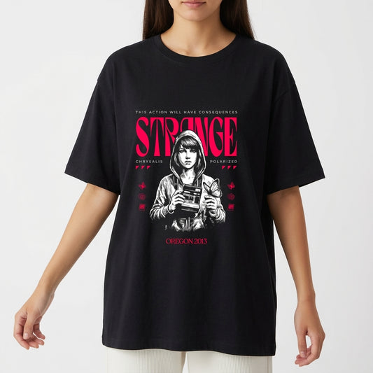 Camiseta com estampa frontal de personagem segurando uma câmera, com itens gráficos ao redor e texto estilizado em destaque, incluindo "Strange" e "Oregon 2013".